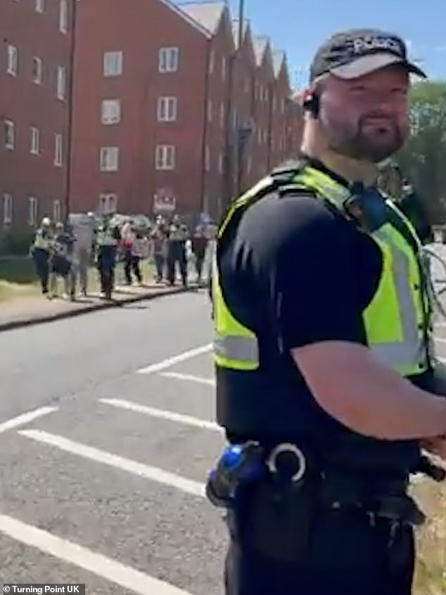An officer is seen standing on one side of the road as colleagues escort counter-protesters