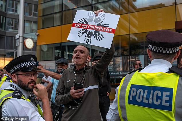 A man holds up a poster during a demonstration outside the Britannia International Hotel in Canary Wharf on July 23