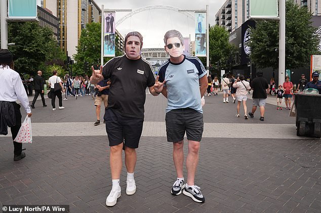 Oasis fans wearing Liam and Noel Gallagher masks pose for a photo outside the stadium, ahead of the first night of the Oasis Live '25 tour opening at Wembley Stadium in London