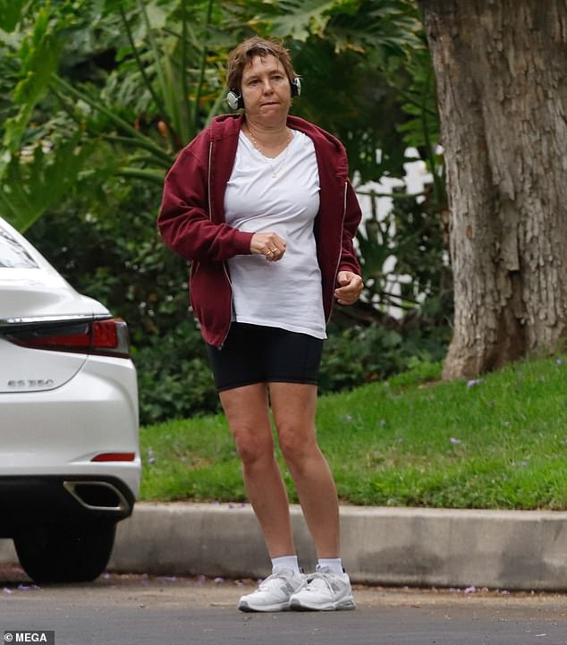 She was dressed for comfort in a white T-shirt, black shorts, a maroon jacket and sneakers with cropped short hair