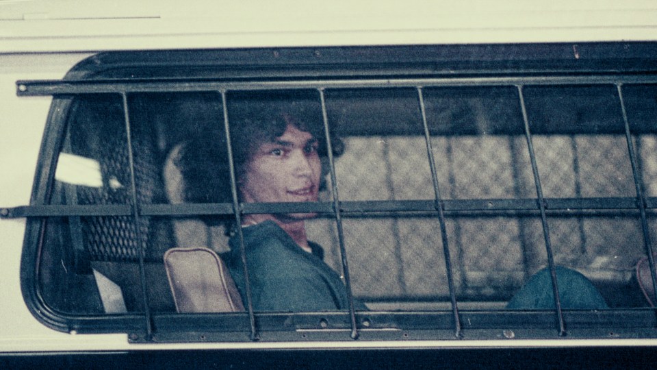 Richard Ramirez, the Night Stalker, seen through a cage in a police vehicle.