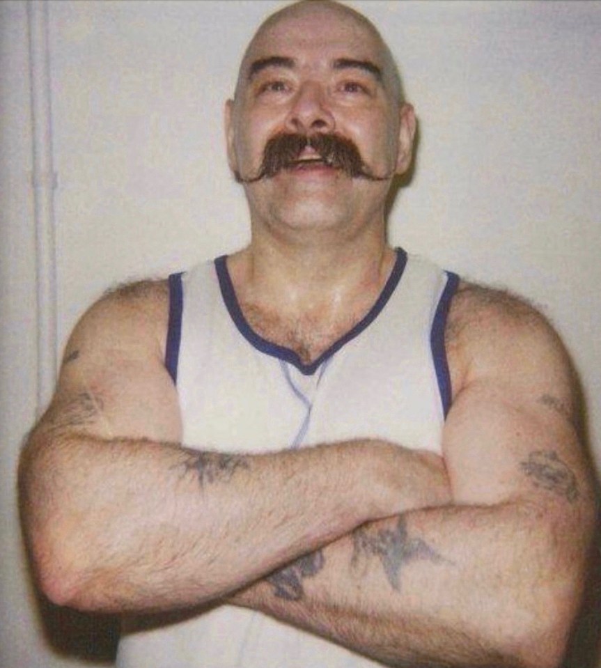 Charlie Bronson, a notorious prisoner, with arms crossed.