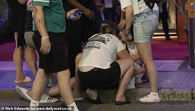 Pictured: A group of friends trying to help a woman up off the floor after a boozy night out. The strip at S'Arenal is lined with large German beerhalls, nightclubs, and even traditional bratwurst and currywurst stalls