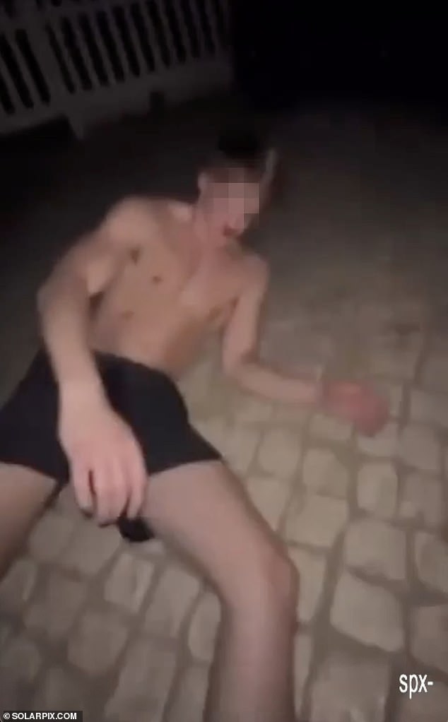 The 18-year-old was lying bloodied and unresponsive as members of the group kick him in the head