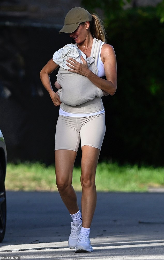 Bündchen showcased her toned legs in a taupe toned pair of leggings with a matching tank top and a billed cap. Her son, about five months old, snuggled up to his mom with help from a beige baby carrier