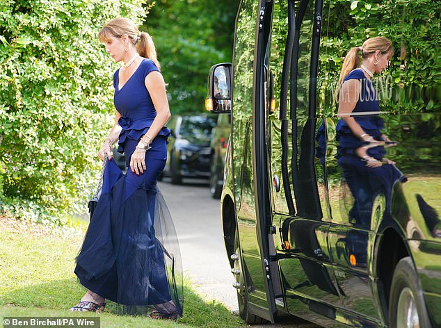 Another guest also wore a royal blue dress topped off with a ponytail as she left a minibus to attend the ceremony