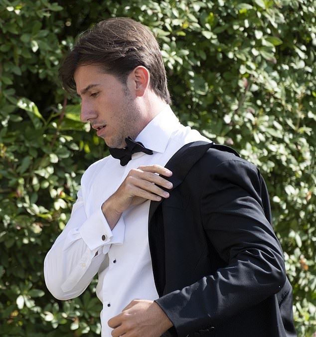 An attendee quickly puts on his dinner jacket as he makes his way to the church doors