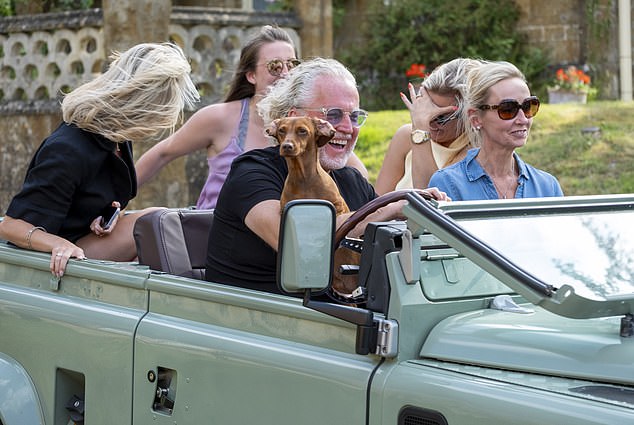 Locals drive by the church St.Michael's and All Angels church. in Great Tew, Oxfordshire