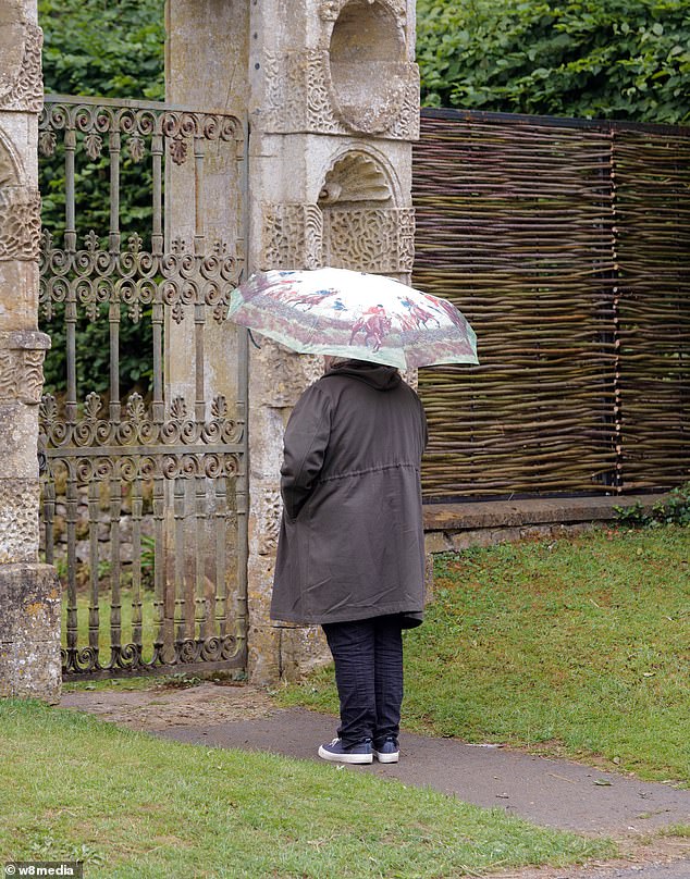 A onlooker looks outside St Michael & All Angels Church in Great Tew, Oxfordshire