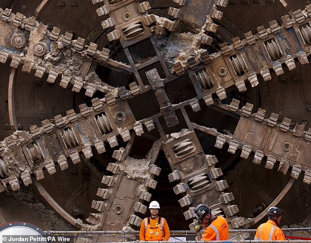 Heavily reinforced ropes, hanging from a huge red metal structure, drag the machine (pictured) from what appears to be an incredibly deep shaft leading down to the tunnel below