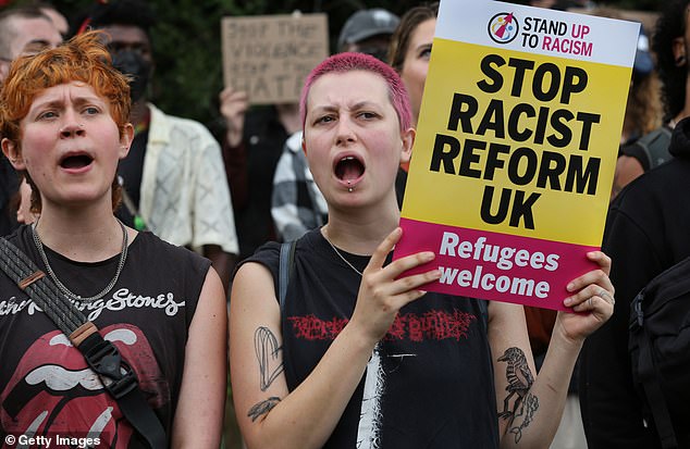 Members of a pro–refugee counter demonstration wave signs and chant by the Brook Hotel in Norwich on Saturday