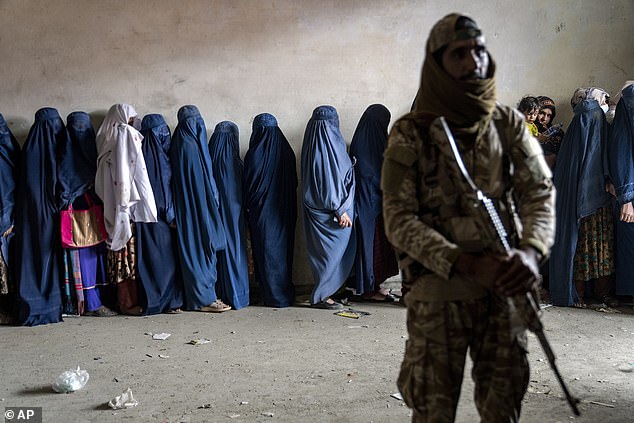 This newspaper revealed earlier this month a British military official catastrophically wrongly shared a database of 100,000 Afghans who had applied for sanctuary in the UK. Pictured: A Taliban fighter stands guard as women wait to receive food rations from a humanitarian aid group in Kabul in May 2023
