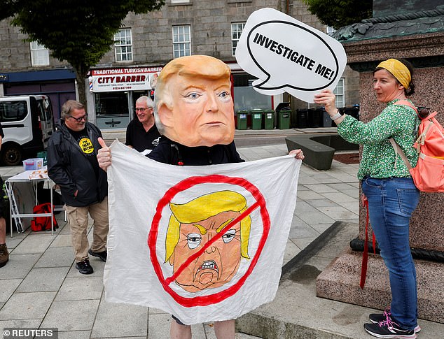 An anti-Trump demonstrator wears a papier-mache head depicting Trump, during a rally organized by the campaign group Stop Trump Coalition
