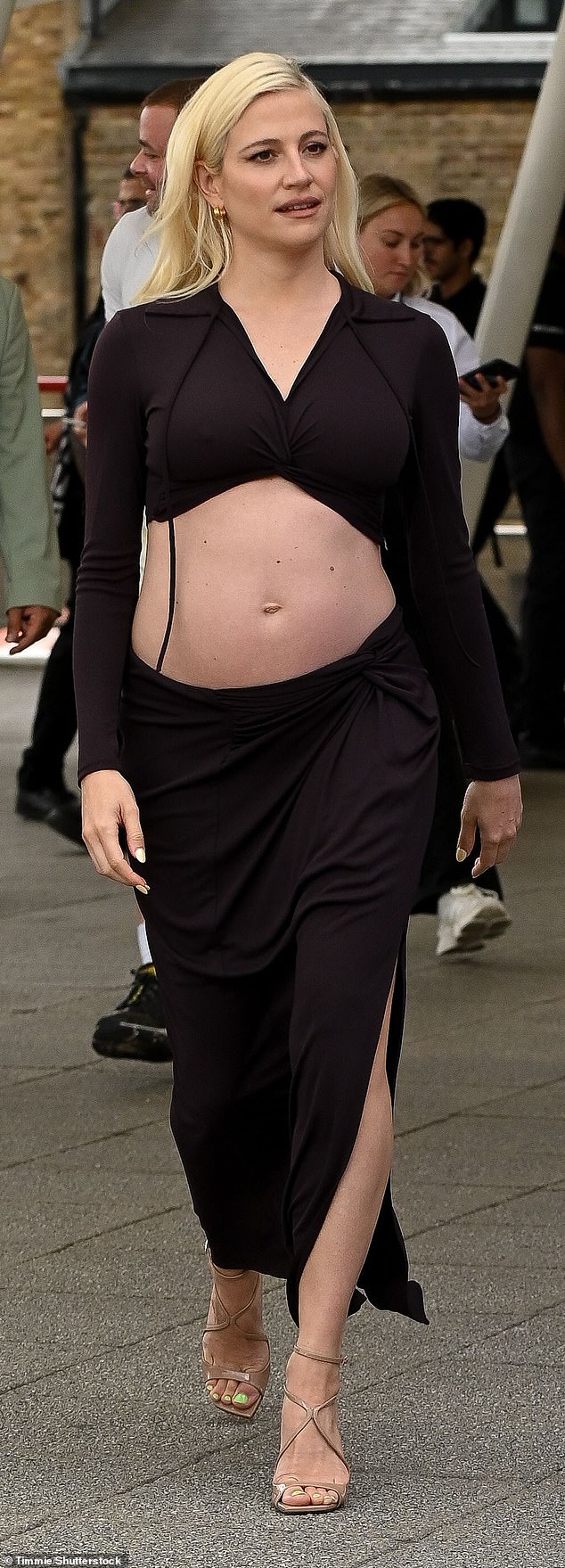 The singer, 34, who recently announced she was expecting her second child with husband Oliver Cheshire, happily showed off her growing bump in a form-fitting skirt and crop top for the event in London on Saturday