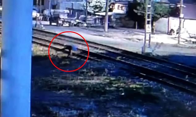 As he nears the railway line, the man's footing appears to more unstable before he takes an almost fatal tumble to the ground, his head hanging over the steel and track ballast
