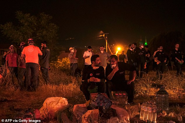 Emergency services and residents rest amid efforts to extinguish a wildfire in a forested area in the Gursu district of Bursa