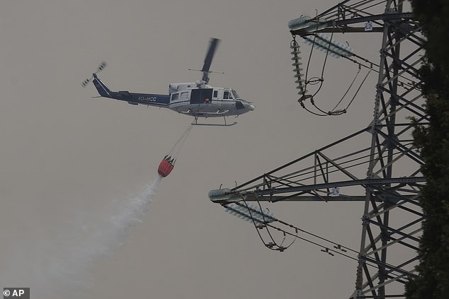 A helicopter throws water on the landscape to battle a wildfire near Montenegro today