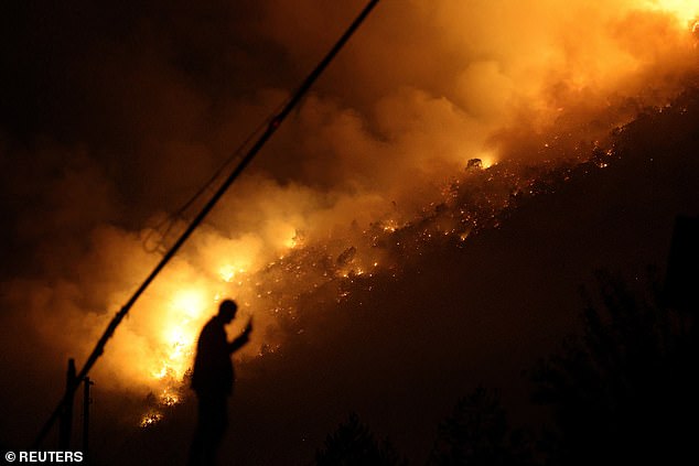 The silhouette of a man is seen through smoke and flames in Bulqiza, Albania, this weekend