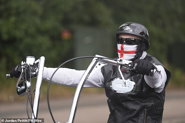 A protester on a motorbike wears a St George's flag mask covering his face