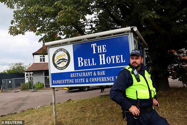 A police officer keeps watch as anti-immigration protesters gather outside The Bell Hotel
