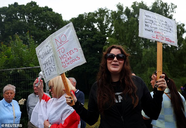 Protesters hold up placards calling for no hotels to be used for migrants near schools