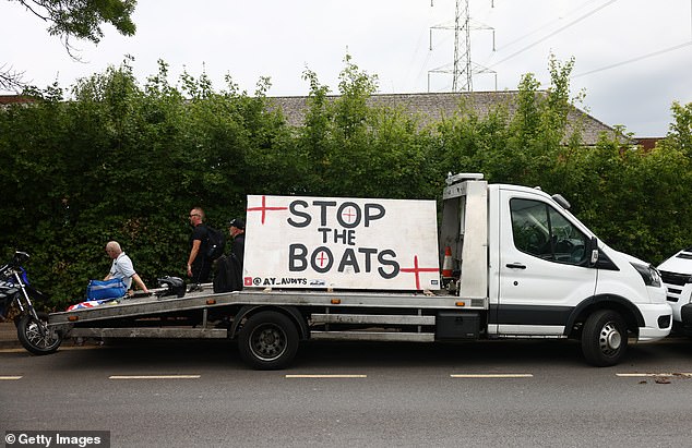 A group of protesters show off a sign which says 'stop the boats' as the Government battles the small boat crisis