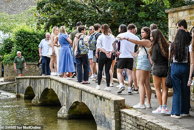 A large group of people cross a bridge in Bourton-on-the-Water - otherwise known as 'Venice of the Cotswolds' due its low bridges and river