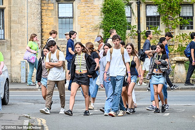 A group walks along the road in the Cotswolds village earlier this month. Bourton-on-the-Water is one of the most popular tourist destinations in the UK