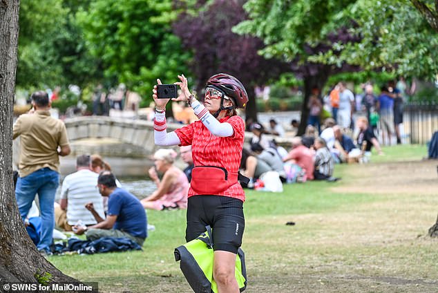 A woman takes a photo of the scenery in Bourton-on-the-Water earlier this month