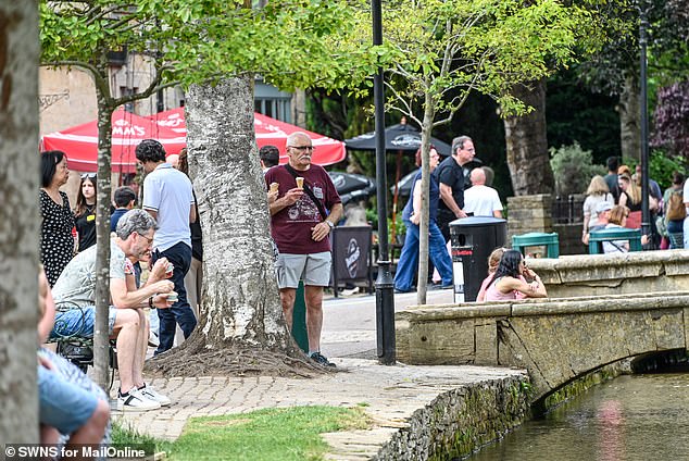 People enjoy an ice cream during the sunny weather in Bourton-on-the-Water this month