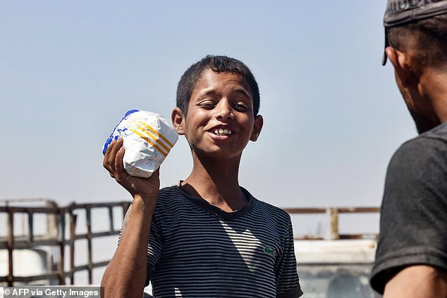 A Palestinian boy reacts as he carries a bag of flour in the al-Mawasi camp in Rafah in the southern Gaza Strip