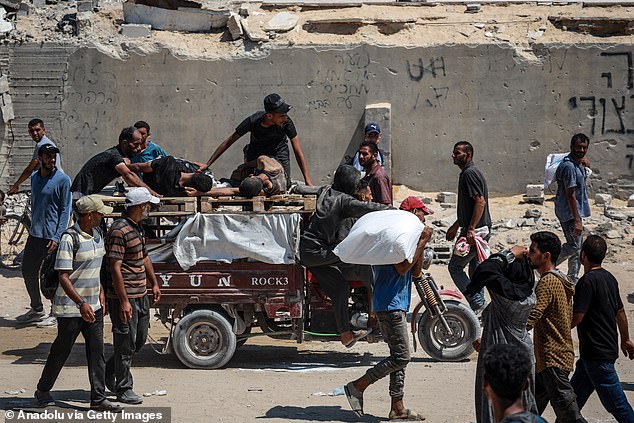 Hundreds of Palestinians carry sacks of flour distributed from aid trucks in the coastal Zikim area of northern Gaza, as they walk away from the distribution point under harsh conditions on July 27, 2025. Amid continued Israeli attacks and a crippling blockade, residents of Gaza are left with scarce access to food and basic supplies