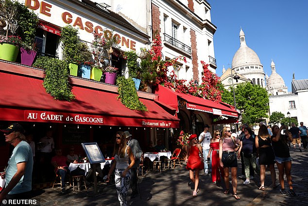 Tourists walk past the restaurant Au Cadet de Gascogne on the Place du Tertre in Montmartre
