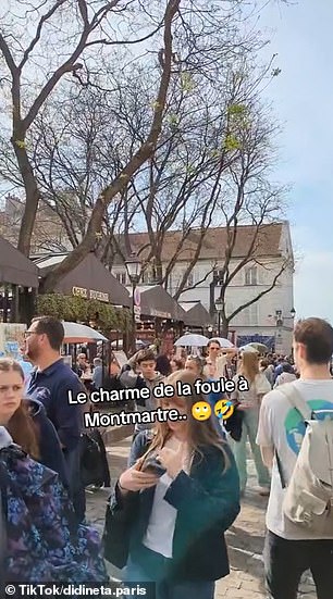 Large crowds walk through the cobbled streets