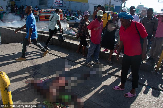 People look at the body of a person who was killed by the members of a criminal gang