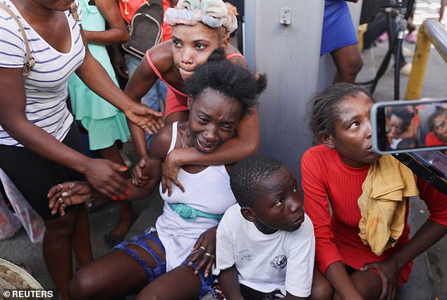 A woman is comforted after the bodies of a group of people shot dead are removed by an ambulance