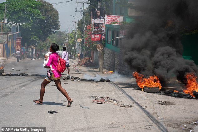 A woman clutches a child as she makes her way to safety after gangs set fire to car tyres