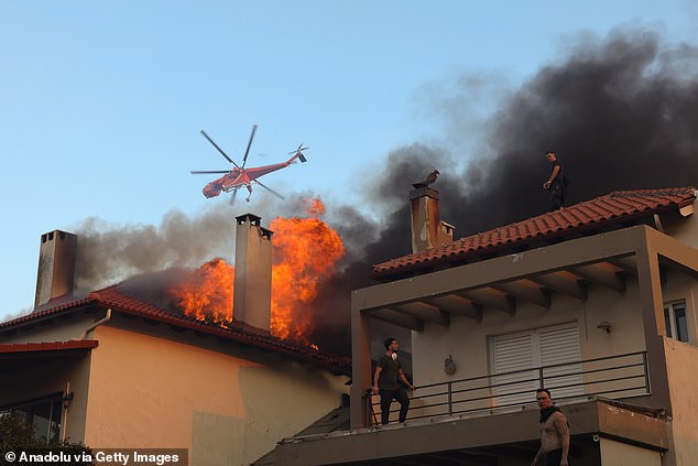 A helicopter tries to get as close to the blaze as it can, while residents in Kryoneri look to help out