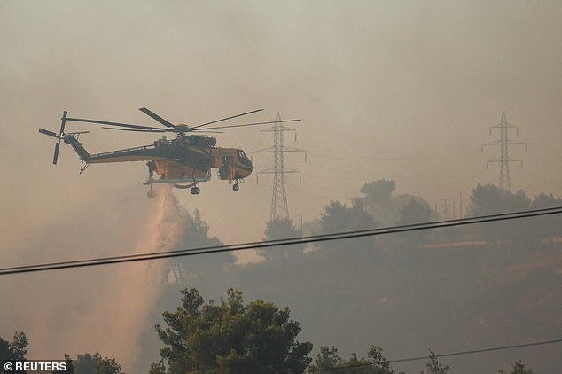 A firefighting helicopter makes a water drop as a wildfire burns in the village of Drosopigi, near Athens this weekend