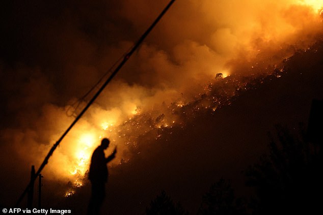 Emergency services and residents rest amid efforts to extinguish a wildfire in a forested area in the Gursu district of Bursa
