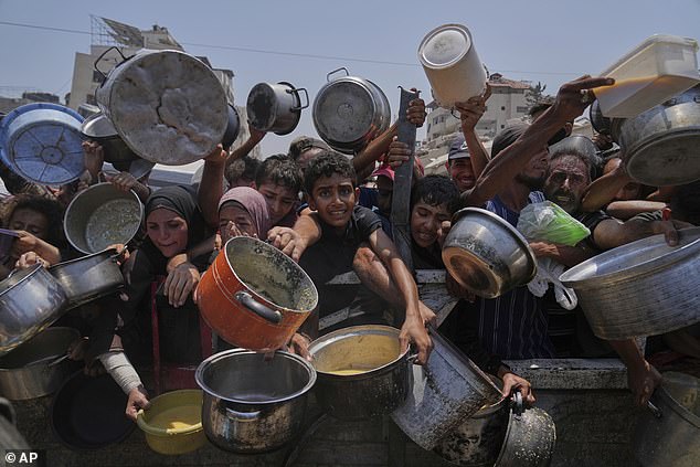 More than 200 MPs have urged him to immediately recognise a Palestinian state. Pictured: Palestinians struggle to get donated food at a community kitchen in Gaza City, northern Gaza Strip, on July 26, 2025