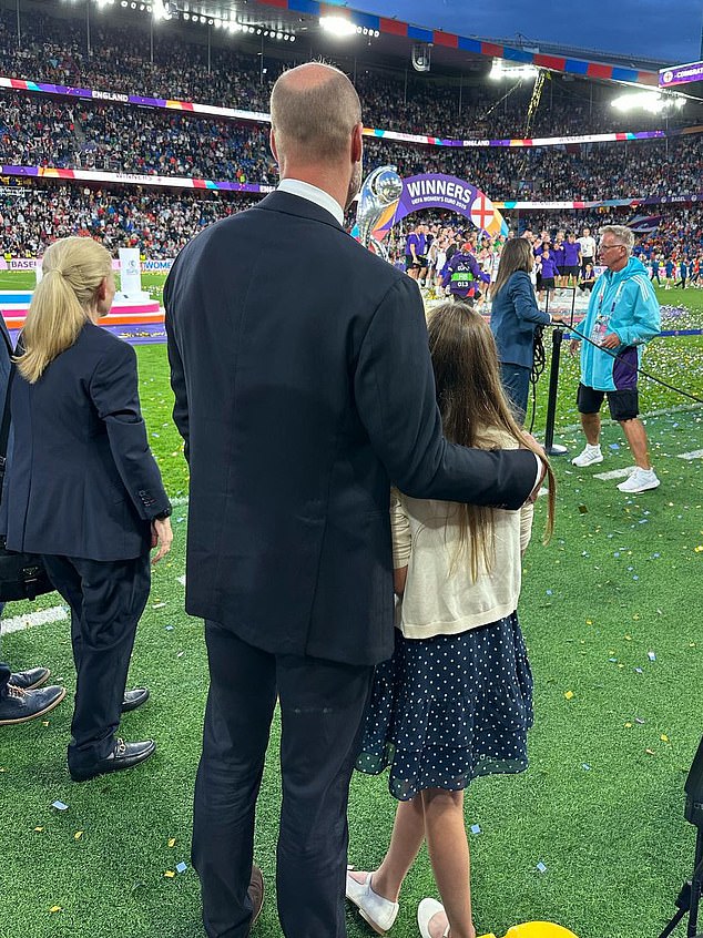 When the team hoisted the trophy as ticker tape rained down, William and Charlotte watched on, with the prince sweetly putting his arm around his daughter (pictured)