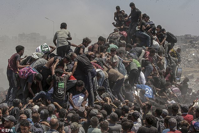 Internally displaced Palestinians try to grab bags of flour from an aid truck near a food distribution point in Zikim, northern Gaza Strip, 27 July 2025