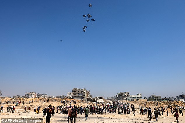 People gather as a C-130 Hercules military transport aircraft drops humanitarian aid on the northern Gaza Strip on July 27