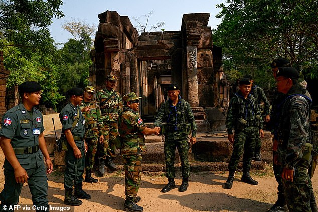 A Cambodian soldier (centre L) shakes hands with a Thai soldier (centre R) at the disputed ancient Khmer temple Prasat Ta Muen Thom, or Prasat Ta Moan Thom in Khmer, on the Cambodian-Thai border in Oddar Meanchey province on March 26, 2025