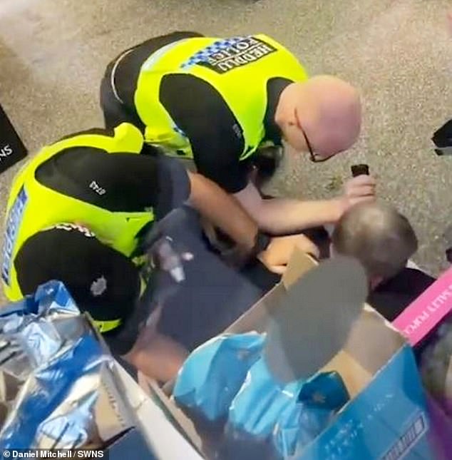 He was subdued by police and a shop security guard after trying to struggle out of the officers' grip
