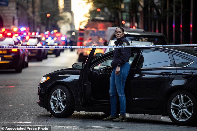 A New York police investigator exits her vehicle at the scene outside a Manhattan office building where two people were shot including a police officer in New York