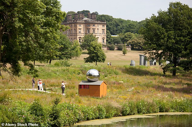 A sculpture by the lower lake standing in front of Bretton Hall in the Yorkshire Sculpture Park
