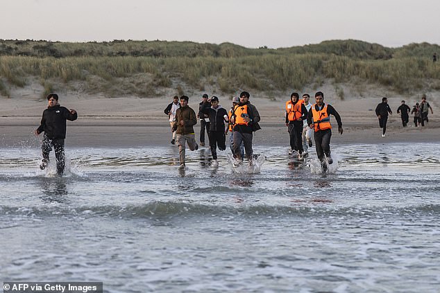 Migrants run towards a smuggler's dinghy off the beach of Gravelines, northern France, this morning