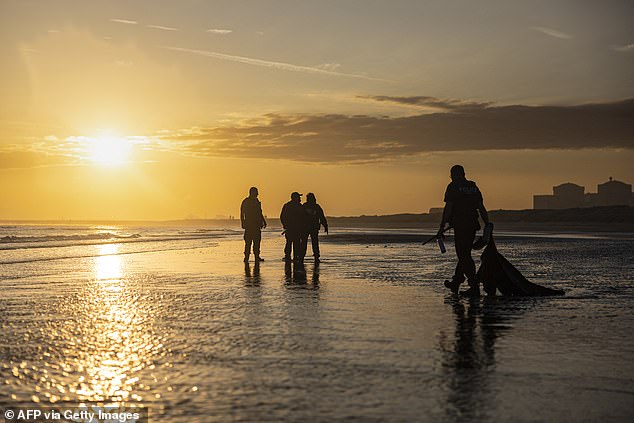French police officers patrol to prevent migrants from boarding a smuggler's inflatable dinghy along Gravelines beach